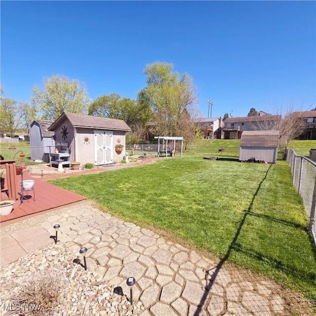 view of yard with a storage unit, an outbuilding, a fenced backyard, and a deck