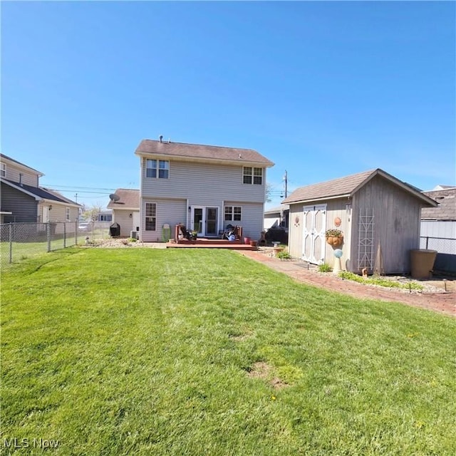 back of house featuring a wooden deck, a yard, a shed, and fence