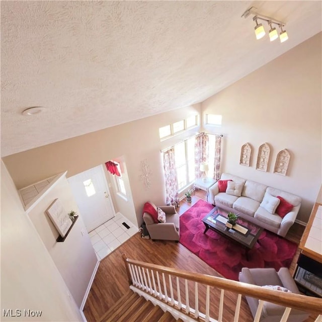living room with vaulted ceiling, wood finished floors, and a textured ceiling