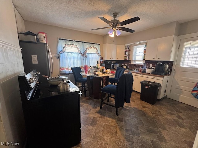 kitchen with black electric range oven, dark countertops, freestanding refrigerator, and white cabinetry