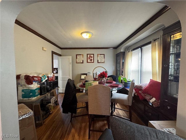 dining area featuring arched walkways, hardwood / wood-style floors, and ornamental molding