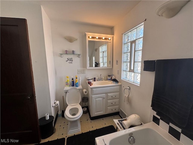 bathroom featuring a washtub, toilet, vanity, and visible vents