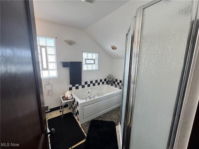 bathroom featuring lofted ceiling, a garden tub, and a stall shower