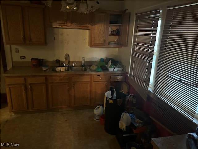 kitchen featuring brown cabinets, a notable chandelier, a sink, and light countertops