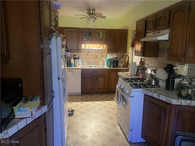 1166 Raymond St NW, Warren, OH 44485 - kitchen with white appliances, under cabinet range hood, tile countertops, a ceiling fan, and backsplash