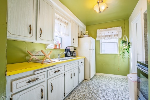 3867 E 177th St, Cleveland, OH 44128 - kitchen featuring white cabinets, range with electric cooktop, light countertops, freestanding refrigerator, and baseboards