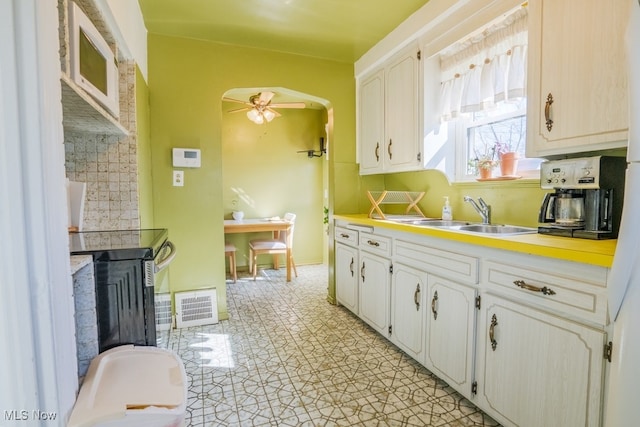 3867 E 177th St, Cleveland, OH 44128 - kitchen with a ceiling fan, a sink, decorative backsplash, light countertops, and visible vents