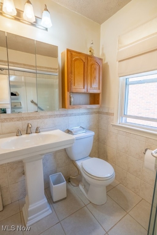 3867 E 177th St, Cleveland, OH 44128 - bathroom with tile patterned floors, a wainscoted wall, toilet, tile walls, and a textured ceiling