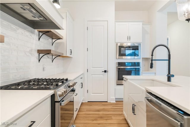 kitchen featuring backsplash, light countertops, a sink, appliances with stainless steel finishes, and custom range hood