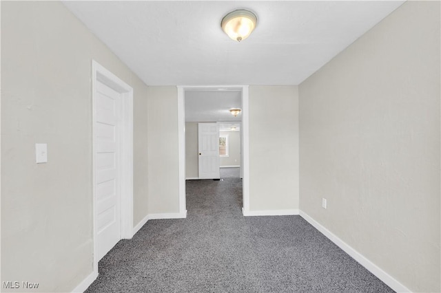 empty room featuring dark carpet and baseboards
