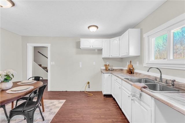 kitchen with white cabinets, a sink, dark wood-style floors, and light countertops