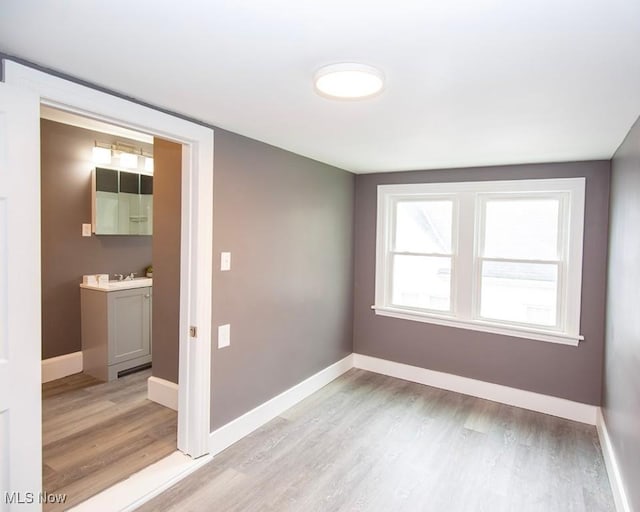 empty room with baseboards and light wood-type flooring