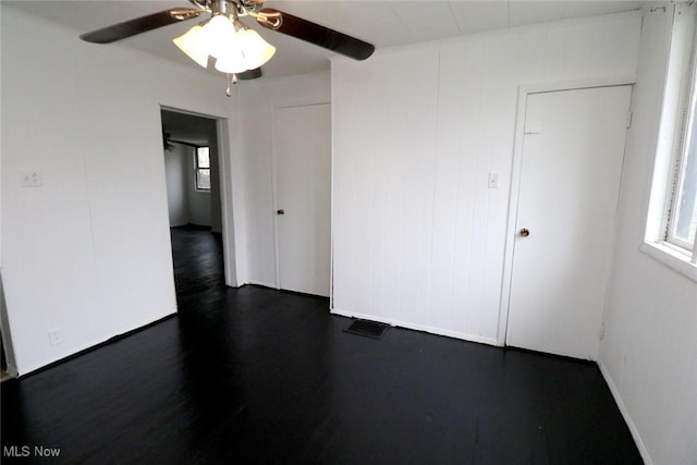 unfurnished room featuring dark wood finished floors, a healthy amount of sunlight, and a ceiling fan