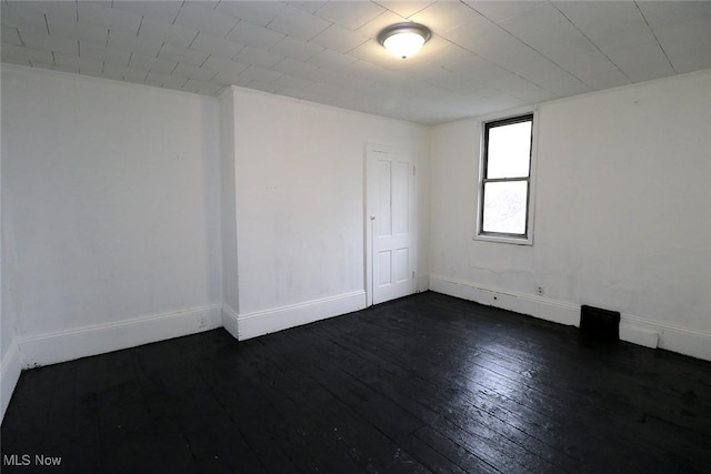 unfurnished room featuring baseboards and dark wood-style floors
