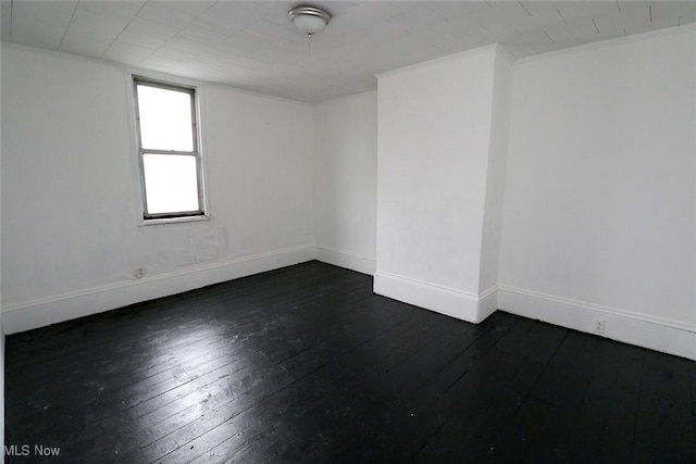 empty room with dark wood finished floors and baseboards