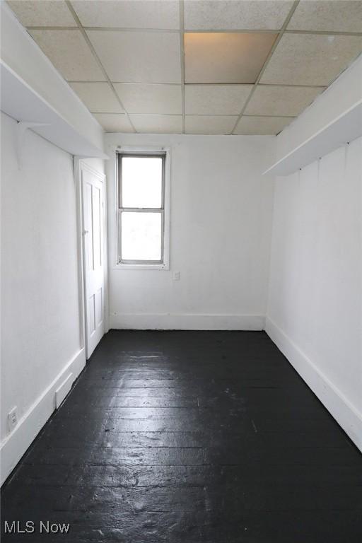 spare room with dark wood-style floors, baseboards, and a drop ceiling