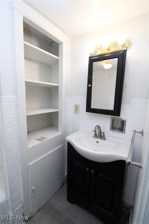 bathroom with wainscoting, vanity, wood finished floors, and tile walls