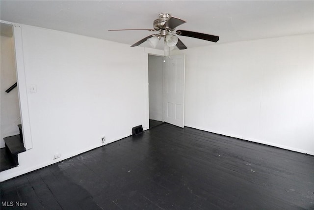 spare room featuring stairway, wood finished floors, and ceiling fan