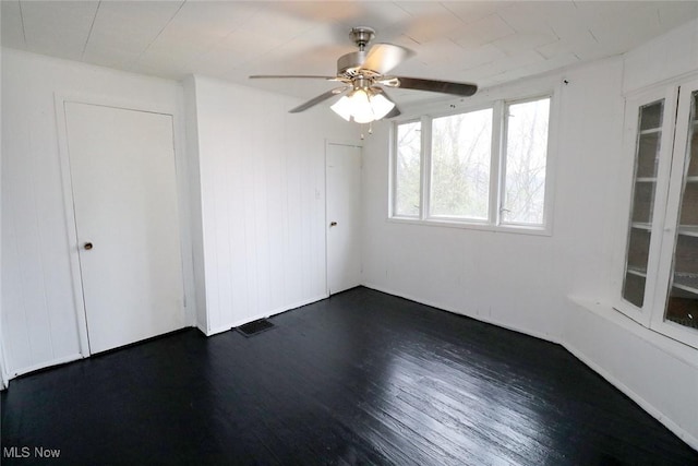 empty room featuring visible vents, ceiling fan, and dark wood finished floors