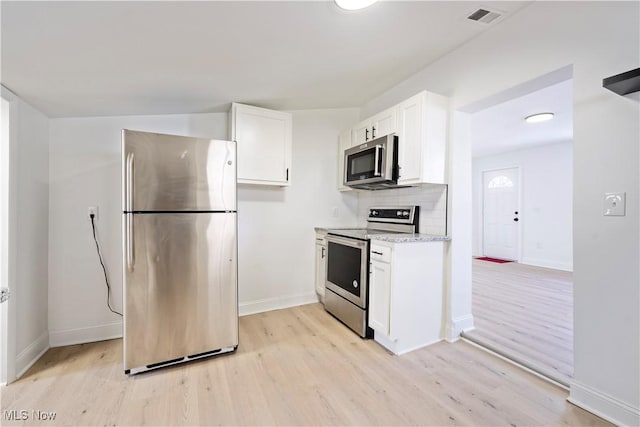 kitchen with white cabinets, light wood finished floors, stainless steel appliances, visible vents, and baseboards