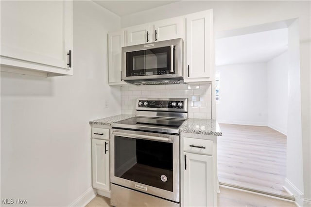 kitchen featuring baseboards, light stone counters, and stainless steel appliances