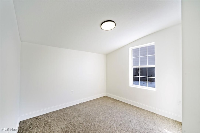 carpeted empty room with vaulted ceiling and baseboards