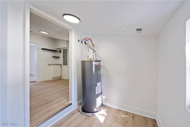 utilities featuring visible vents, electric panel, and electric water heater
