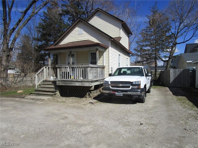view of front of home with a porch, dirt driveway, and fence