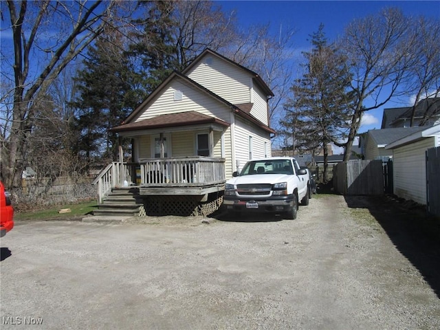 bungalow featuring fence, driveway, and covered porch