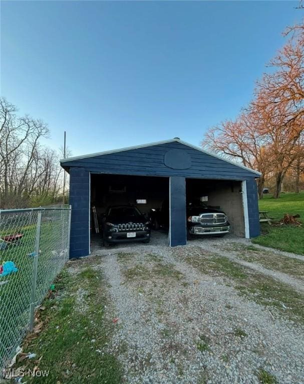 142 W Main St, Hopedale, OH 43976 - view of car parking with a garage, dirt driveway, and fence