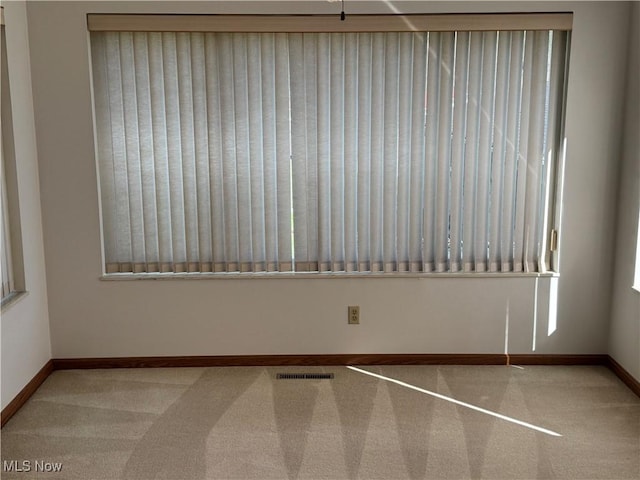carpeted empty room featuring visible vents and baseboards