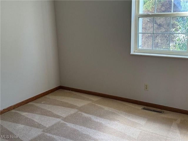 unfurnished room featuring baseboards, visible vents, and light colored carpet