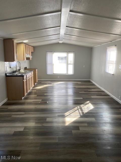 interior space featuring vaulted ceiling, baseboards, and plenty of natural light