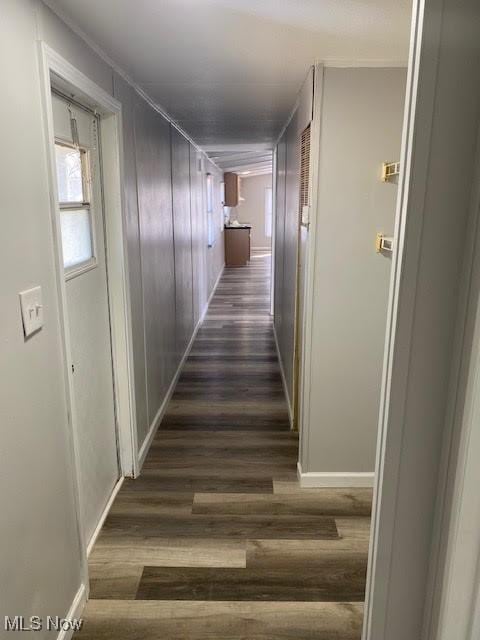 hallway featuring baseboards and dark wood-style floors
