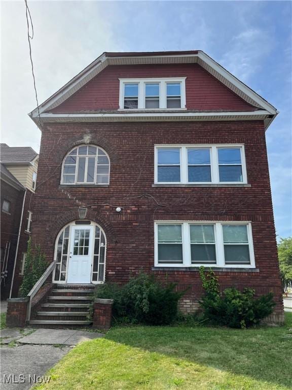 view of front of house featuring entry steps, brick siding, and a front yard