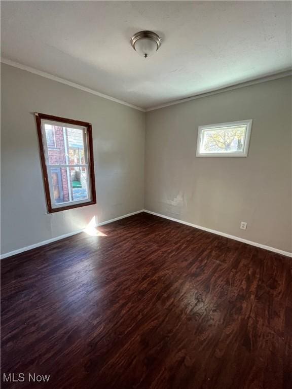 unfurnished room with baseboards, crown molding, and dark wood-style floors