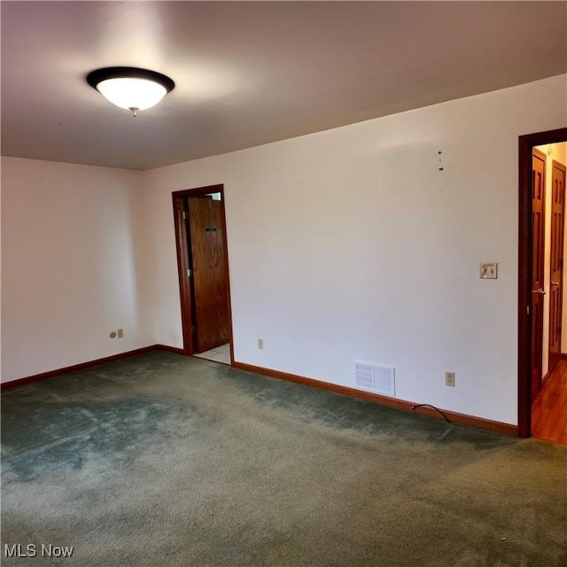carpeted empty room featuring baseboards and visible vents