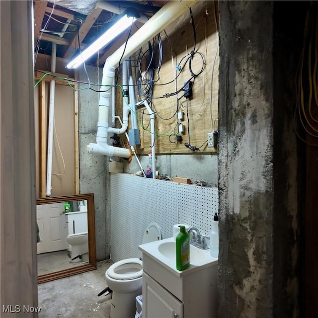 interior space featuring unfinished concrete floors, toilet, and vanity