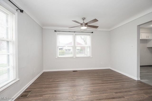 unfurnished room featuring a ceiling fan, dark wood-style flooring, a healthy amount of sunlight, and visible vents