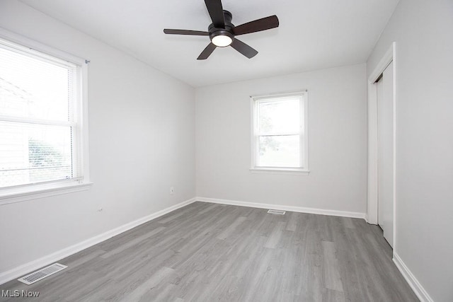spare room featuring wood finished floors, visible vents, ceiling fan, and a healthy amount of sunlight