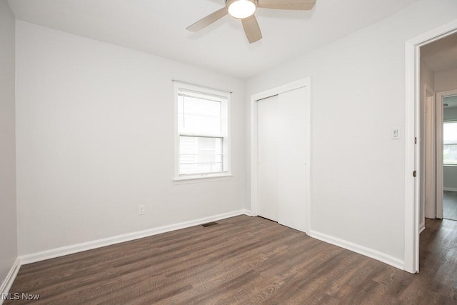 unfurnished bedroom featuring a closet, visible vents, dark wood-style floors, and multiple windows