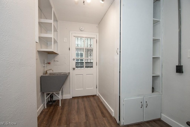 interior space featuring a textured wall, baseboards, and dark wood-style floors