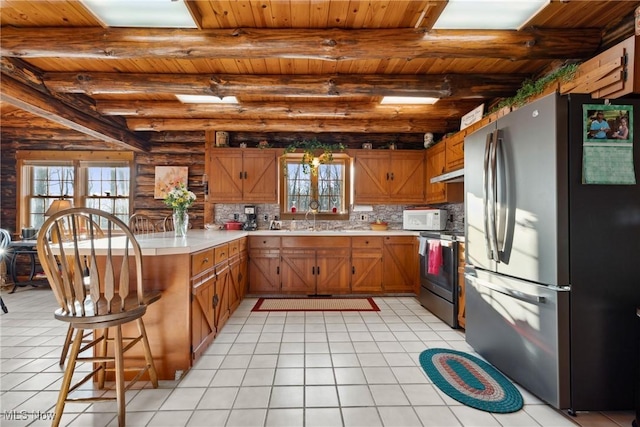 kitchen with light countertops, wooden ceiling, a peninsula, appliances with stainless steel finishes, and log walls