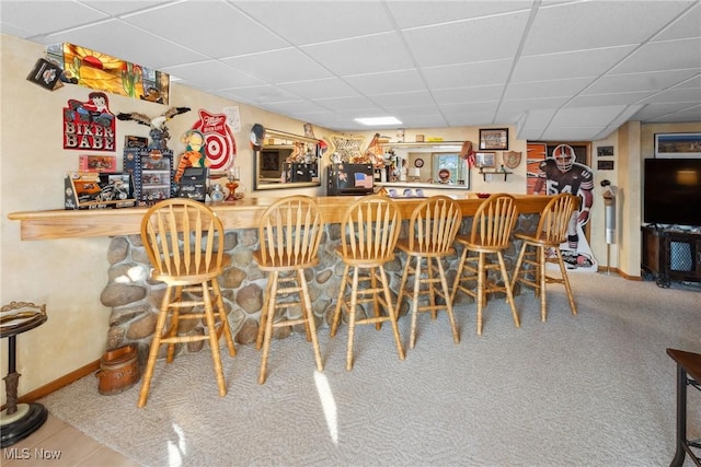 bar with a dry bar, baseboards, carpet floors, and a drop ceiling