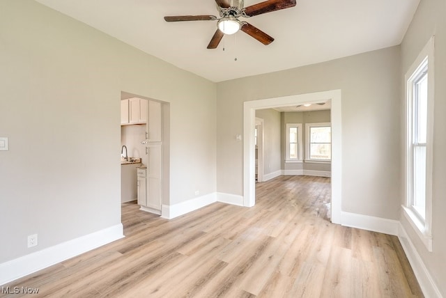 unfurnished room with ceiling fan, baseboards, and light wood-style flooring