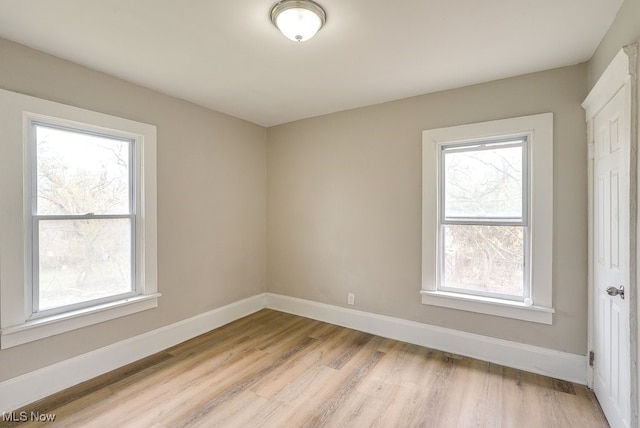 spare room with baseboards and light wood-style floors