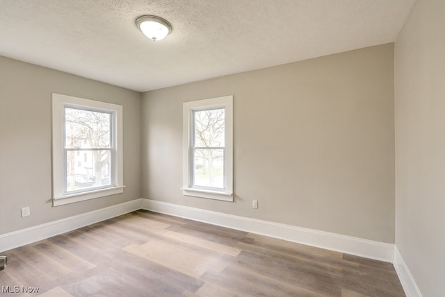 unfurnished room featuring plenty of natural light, baseboards, and wood finished floors