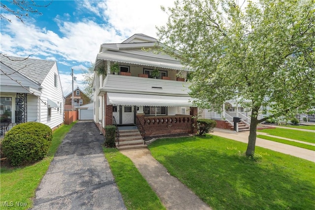 view of front of property with an outdoor structure, covered porch, a front yard, and a garage