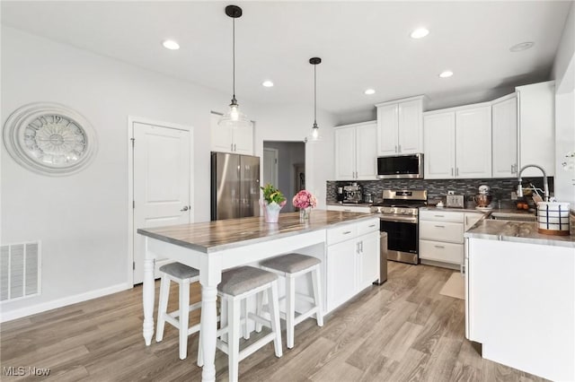kitchen with a center island, a sink, visible vents, backsplash, and appliances with stainless steel finishes