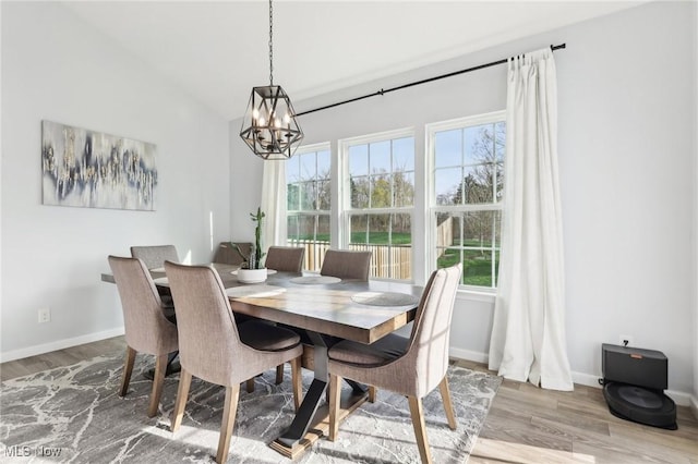 dining area featuring wood finished floors, a healthy amount of sunlight, baseboards, and an inviting chandelier